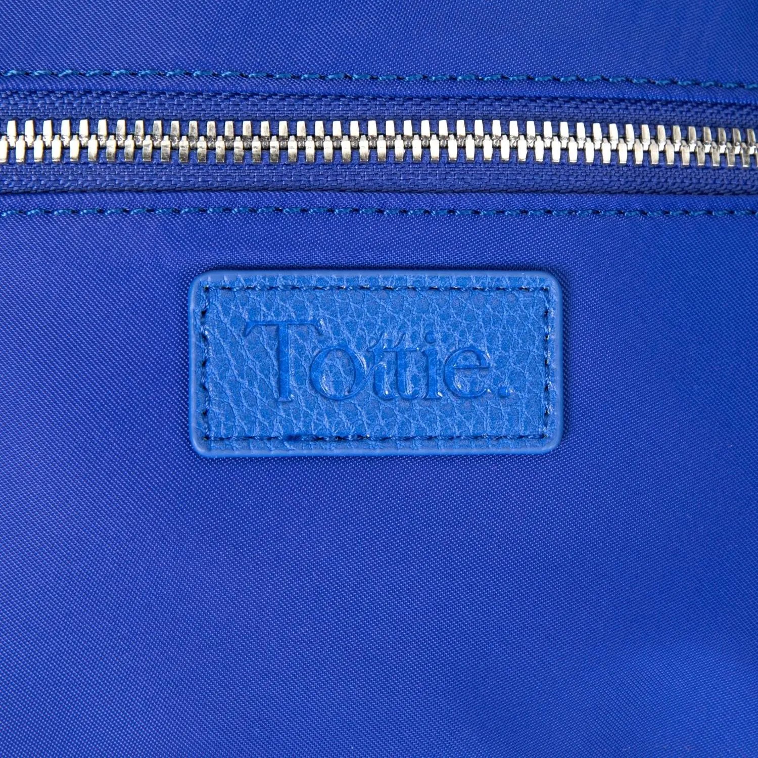 Close-up of Tottie logo embossed on royal blue nylon bum bag
