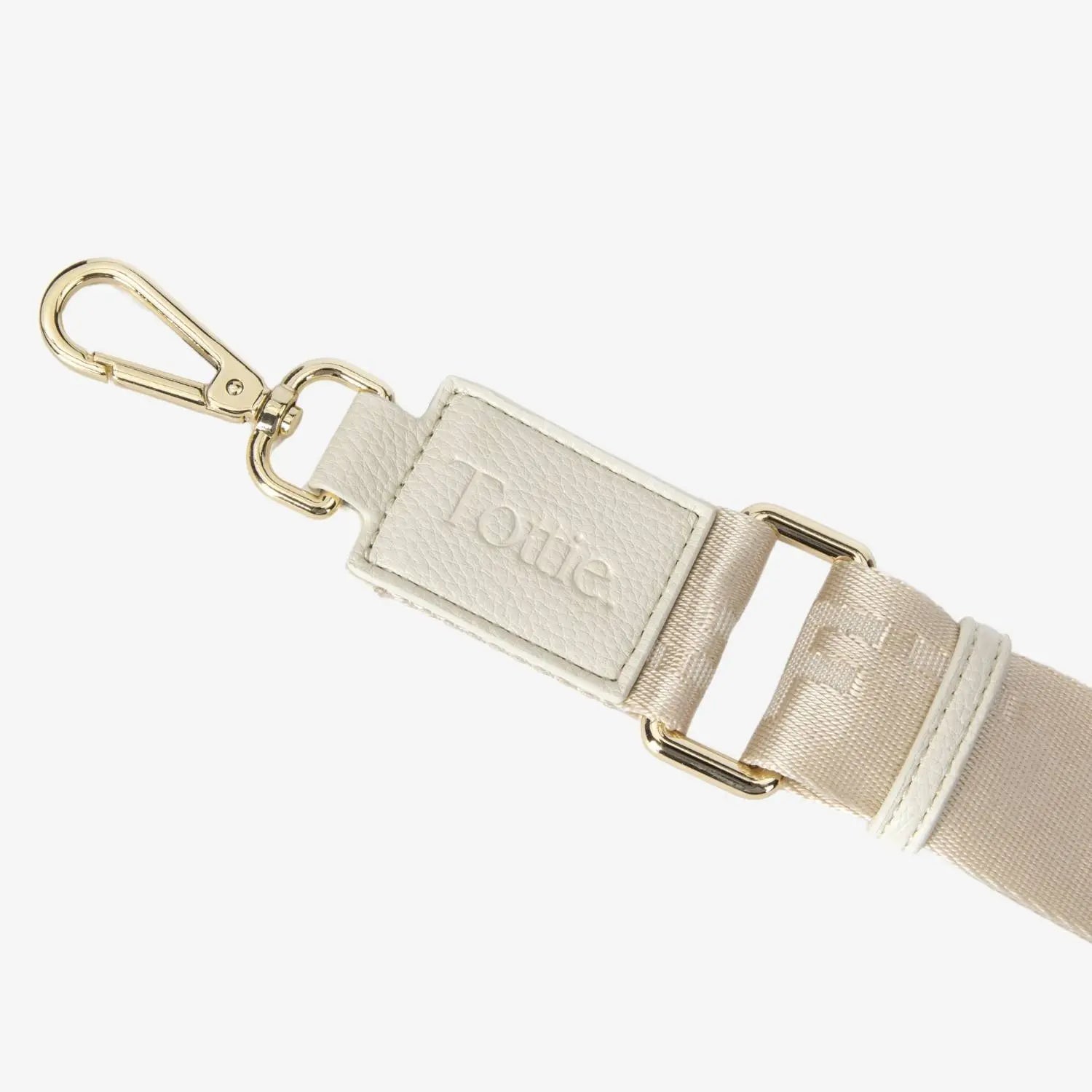 Detailed view of hardware featuring embossed Tottie logo on cream nylon bum bag against white backdrop.