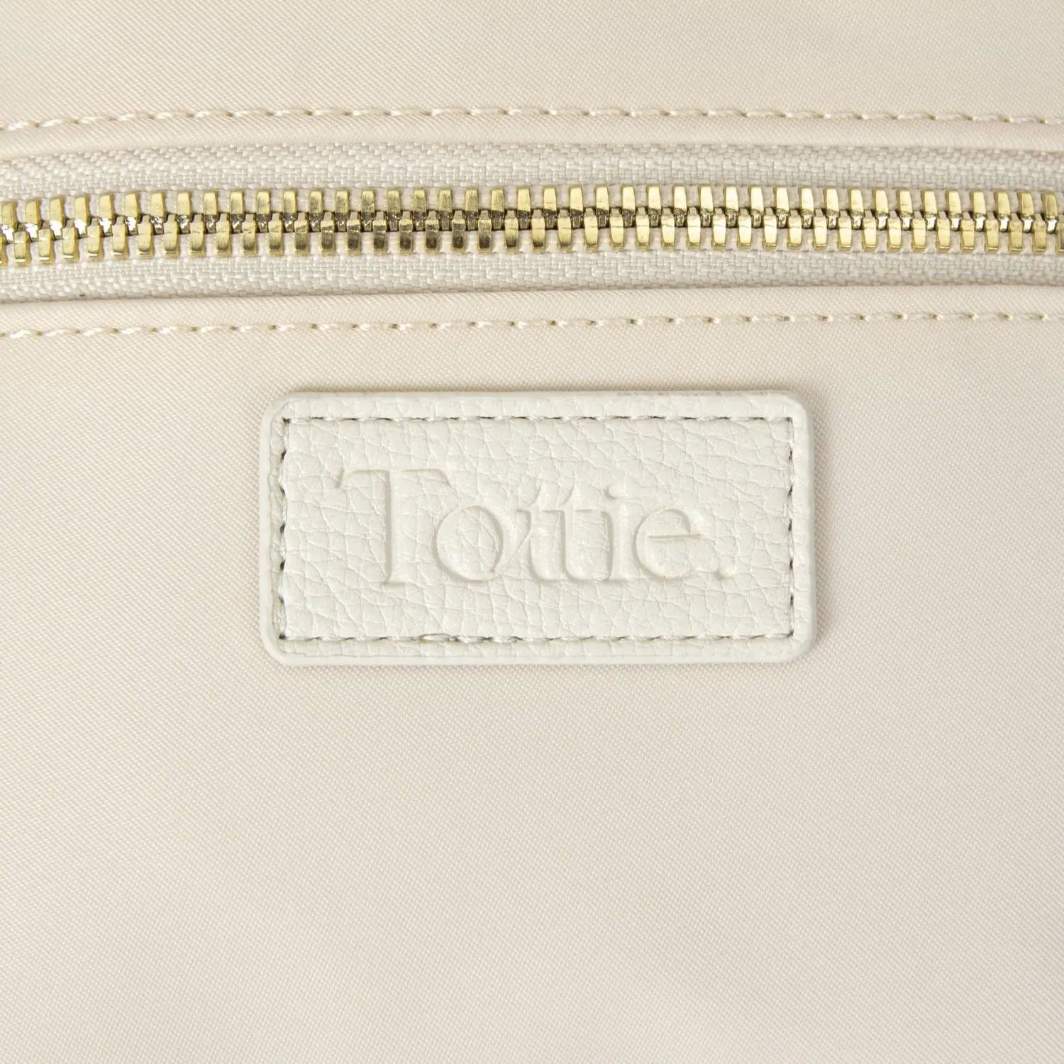 Zoomed-in look at Tottie logo embossed on cream-coloured nylon bum bag on white background.
