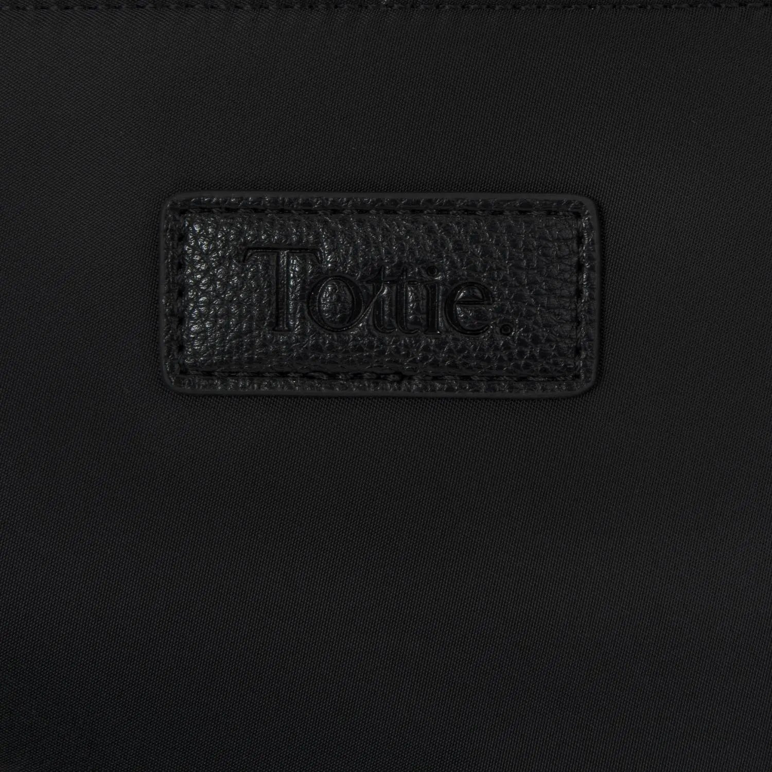 Embossed Tottie logo close-up on black nylon tote bag with cream strap, photographed on white background