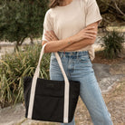 Black nylon tote bag with cream strap close-up highlighting material and design.