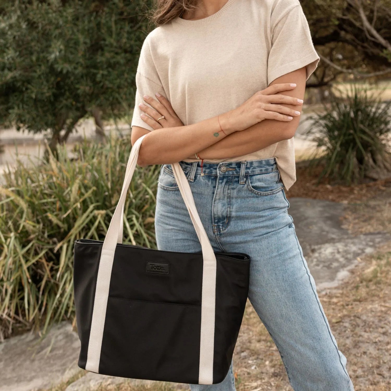 Black nylon tote bag with cream strap close-up highlighting material and design.