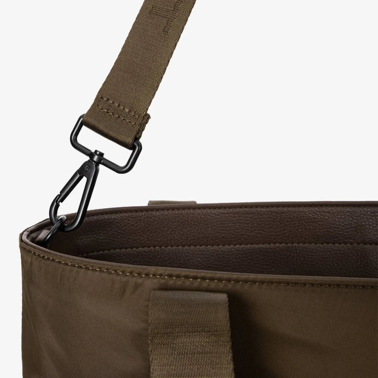 Close-up of hardware strap on brown nylon tote bag, showing metal fittings and reinforced stitching