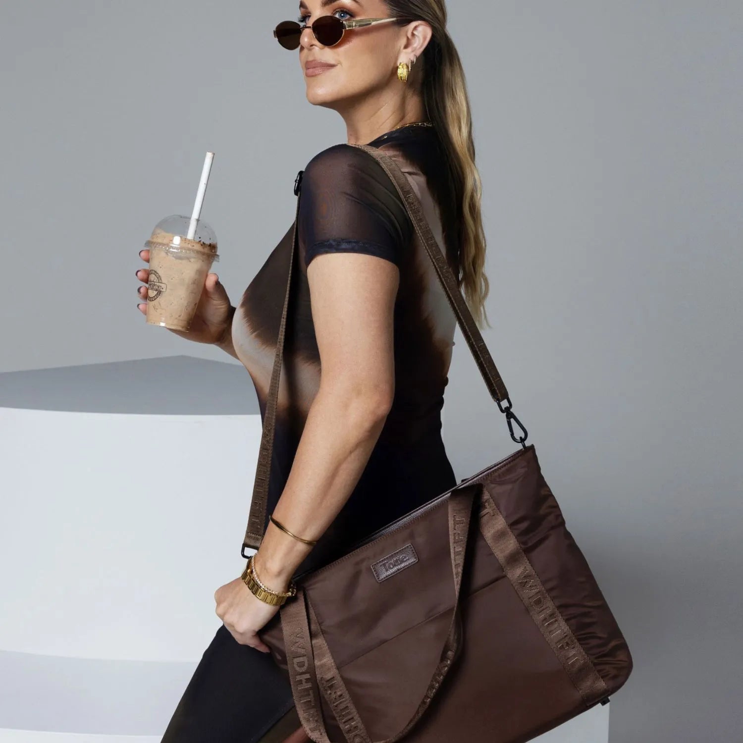 Casual look of woman wearing brown top and shades with brown nylon tote bag.