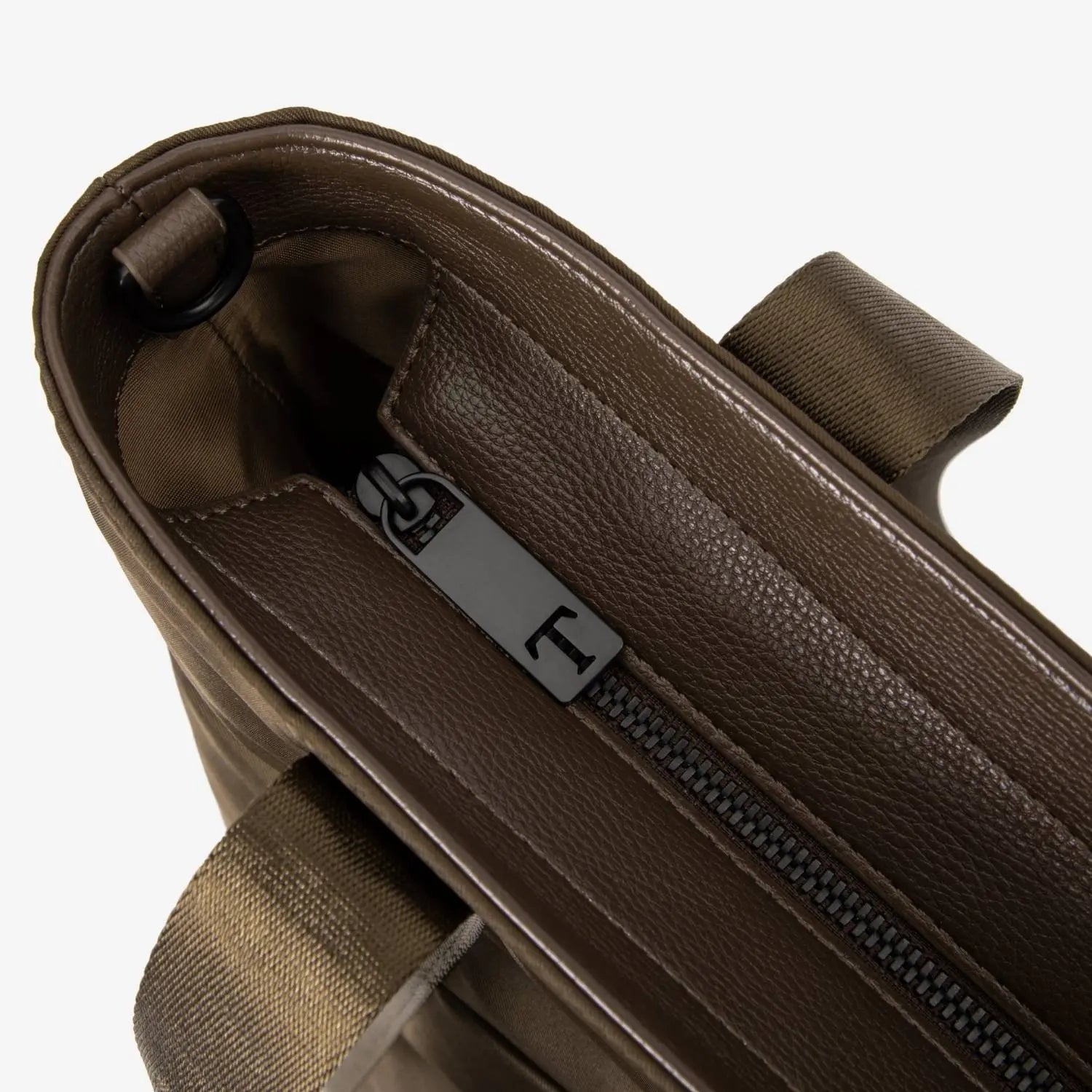 Close-up of zipper with letter T on brown nylon tote bag, showing branded hardware detail