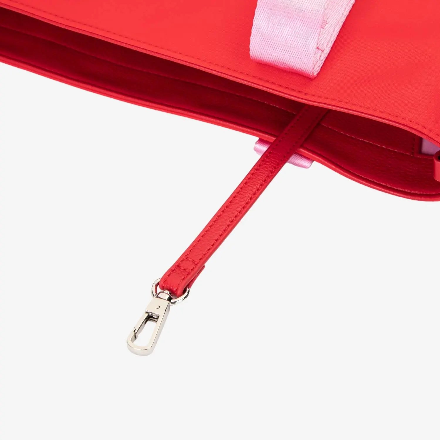 Zoomed-in image of bag hardware and pink strap with WDHTFT embossing on red nylon tote bag against white background.