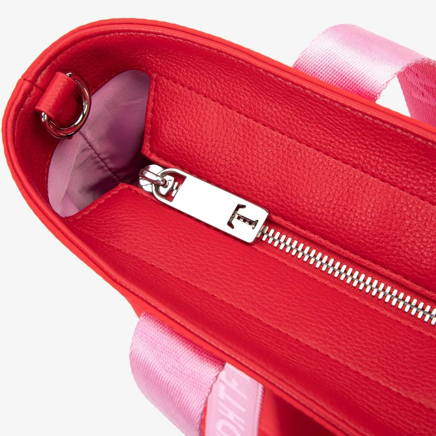 Detailed zipper view of red nylon tote bag with T branding and pink WDHTFT-embossed strap, photographed on white backdrop