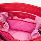 Zoomed-in inside look of red nylon tote bag featuring embossed Tottie logo and pink strap with WDHTFT embossing