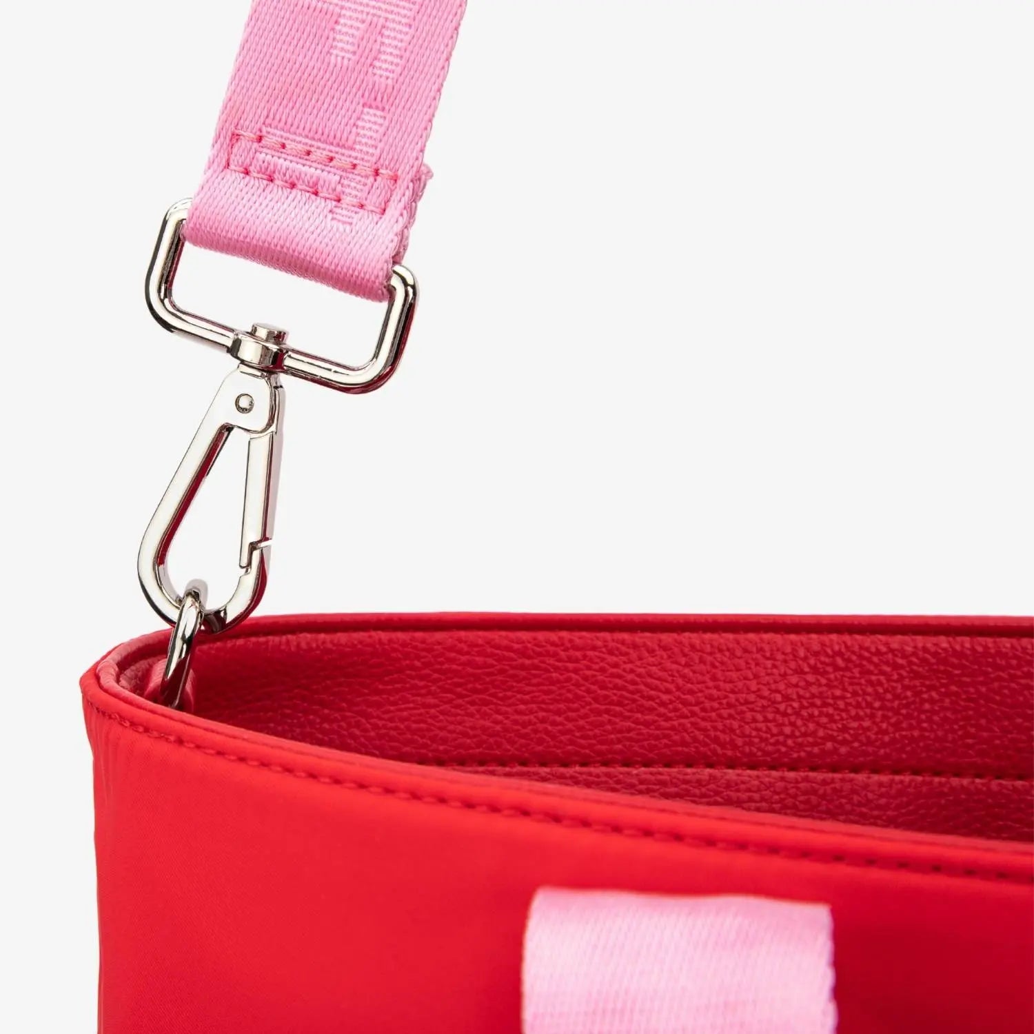 Close-up of pink strap with WDHTFT embossing on red nylon tote bag against white background
