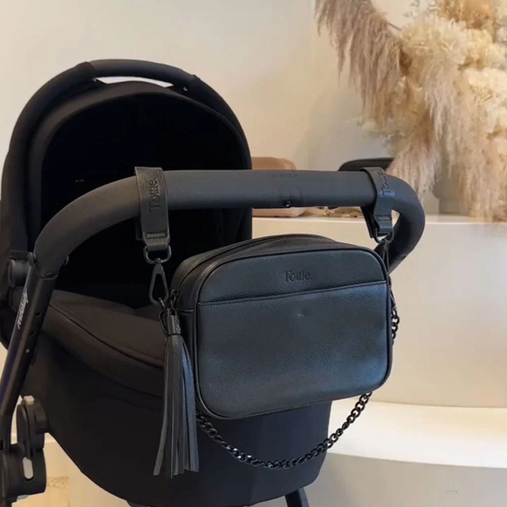 Black vegan leather pram clips and matching crossbody bag attached to a pram stroller – sleek and functional for modern mums