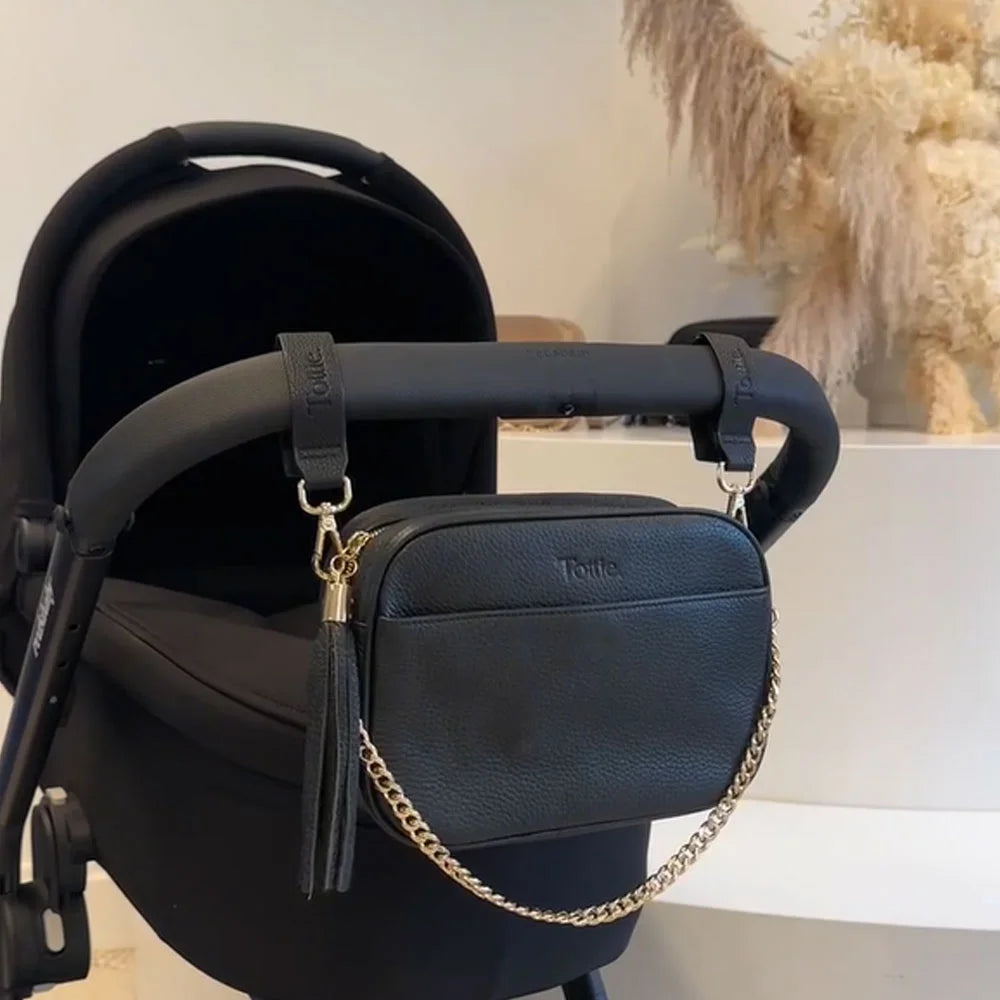Pram stroller with black crossbody bag and pram clips in vegan leather and gold hardware – sleek accessories for organised parenting.