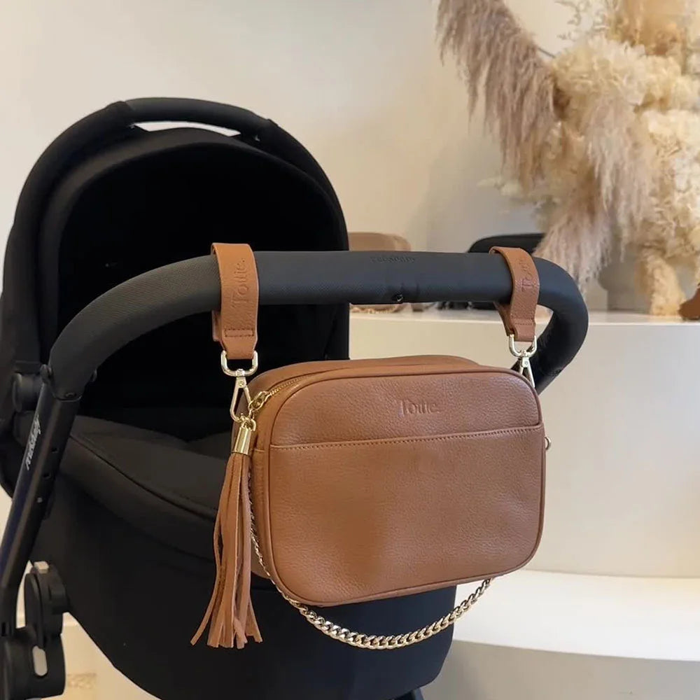 Tan vegan leather pram clips and matching crossbody bag attached to a pram stroller – perfect for stylish mums on the go
