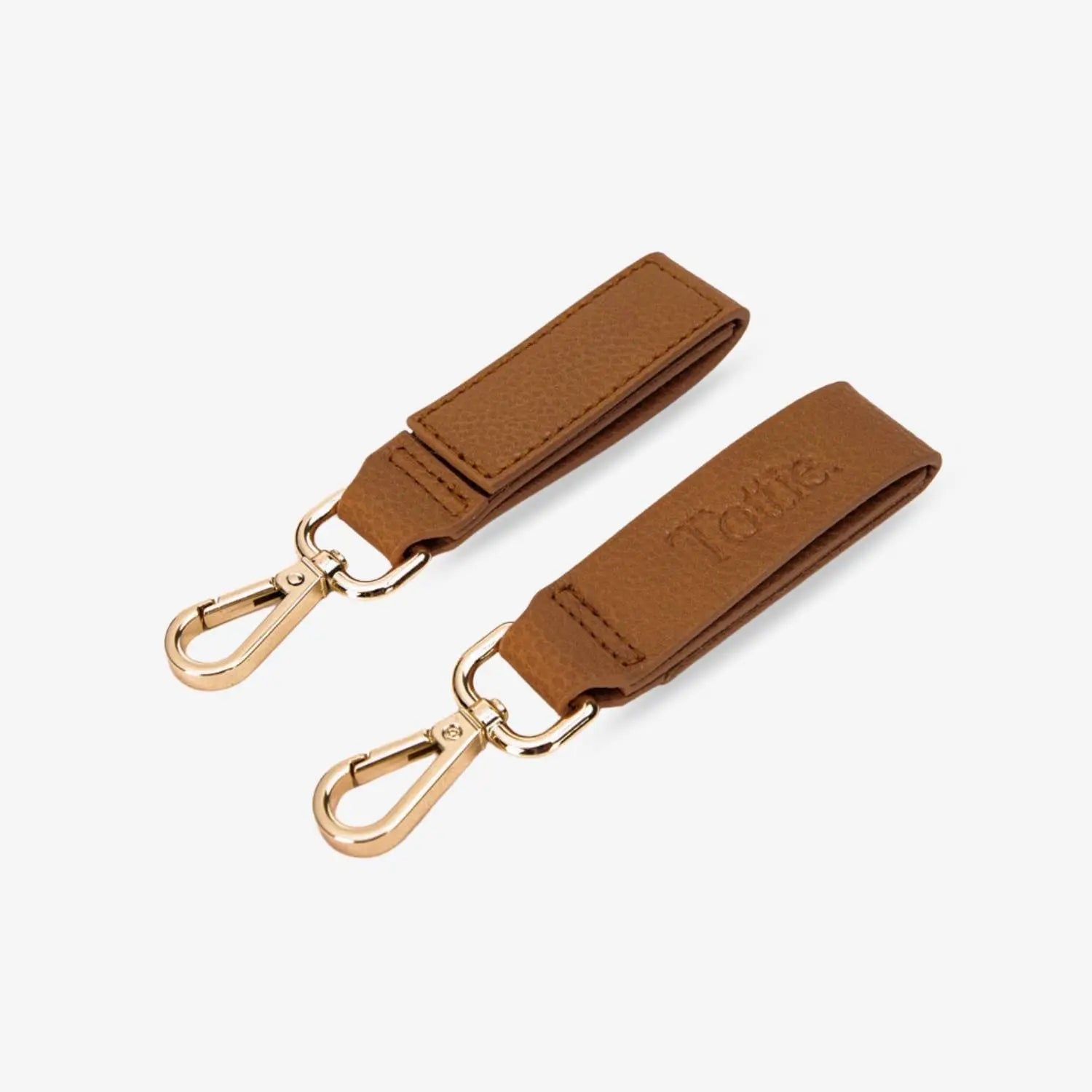Pair of tan pram clips with gold hardware on white background – stylish and secure accessories for prams.