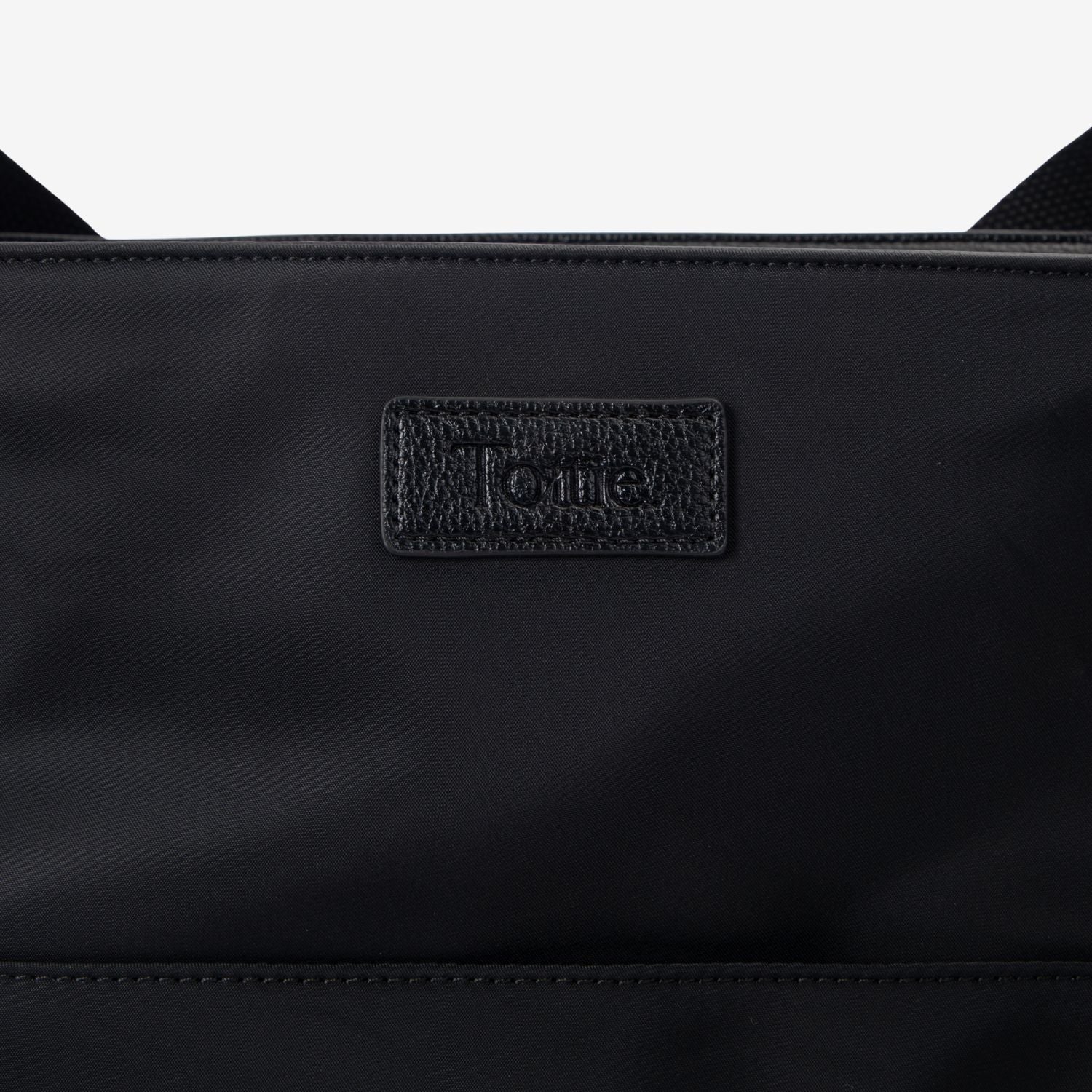 Black tote bag with a Tottie logo on a white background