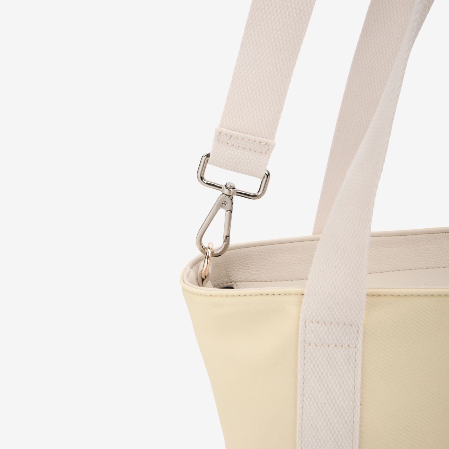 Close-up of a yellow nylon tote bag with a white strap and silver clasp on a light gray background.