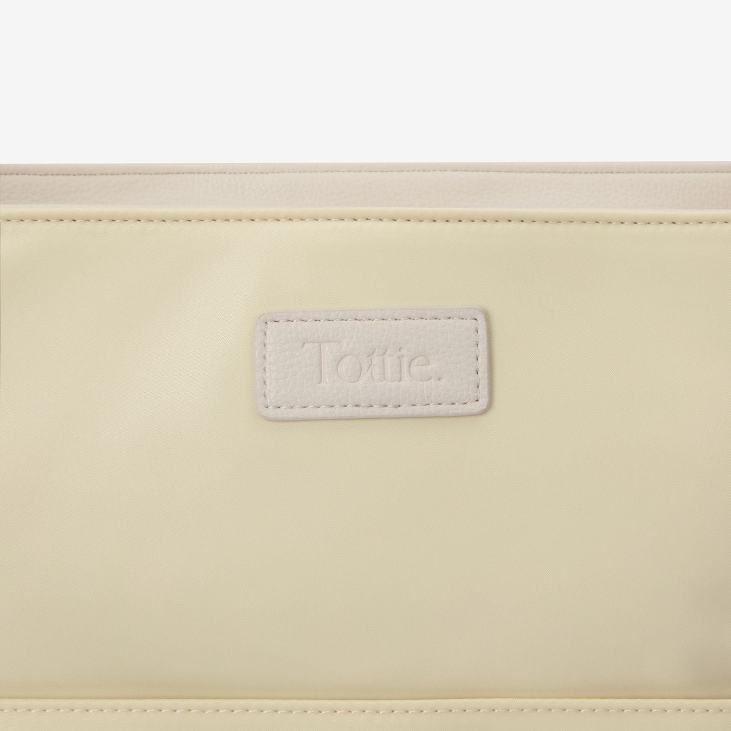 Close-up of a pastel yellow tote bag with a visible brand label on a white background