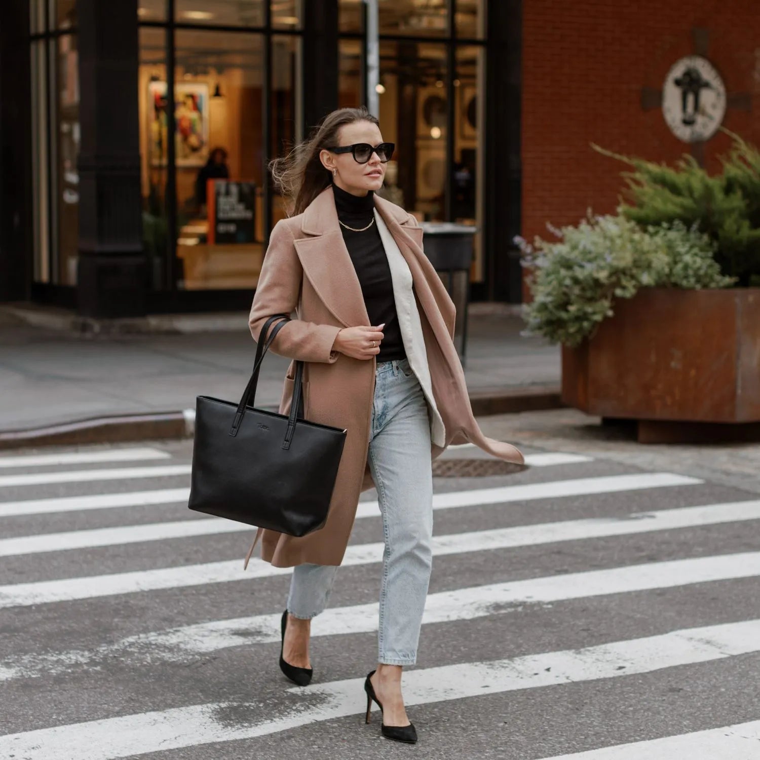 Professional woman with black tote bag walking across a busy street.