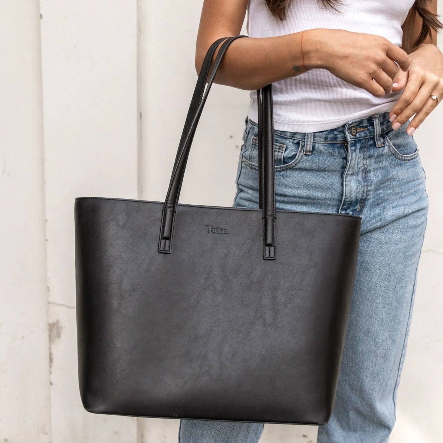 Detailed view of a sleek black tote bag with smooth vegan leather finish.