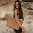 Side angle of a woman with a tan tote bag over her shoulder.