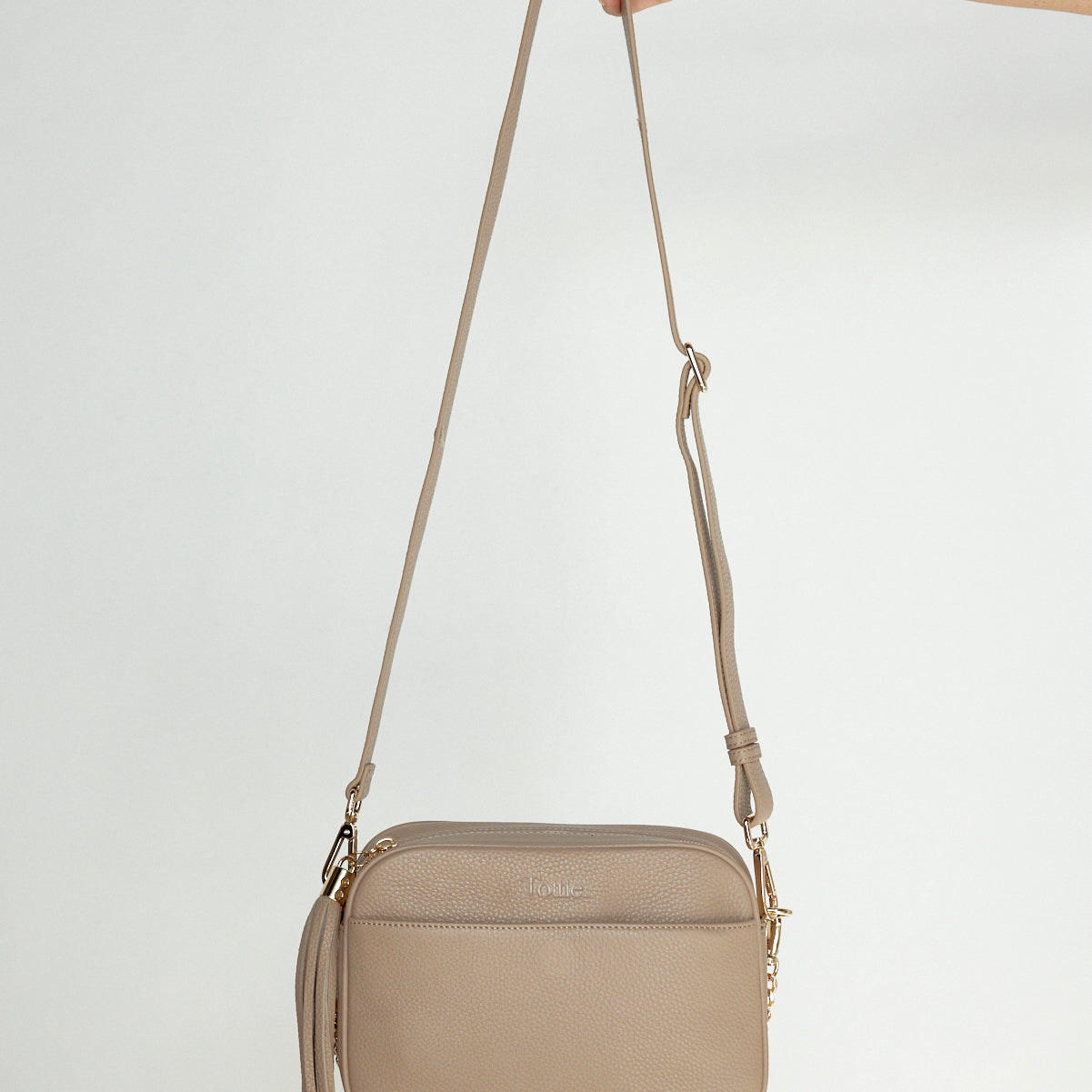 Woman Holding Bestie Stone Leather Crossbody Bag with Gold Chain Strap and Tassel from Tottie