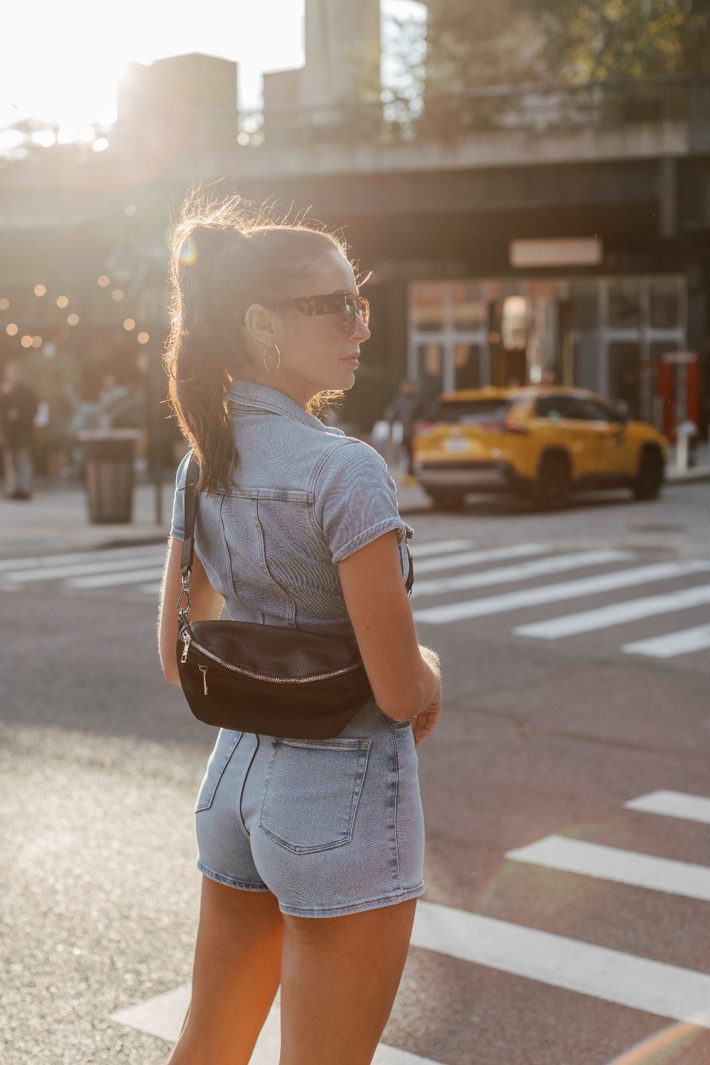 A woman crosses the street carrying a bum bag