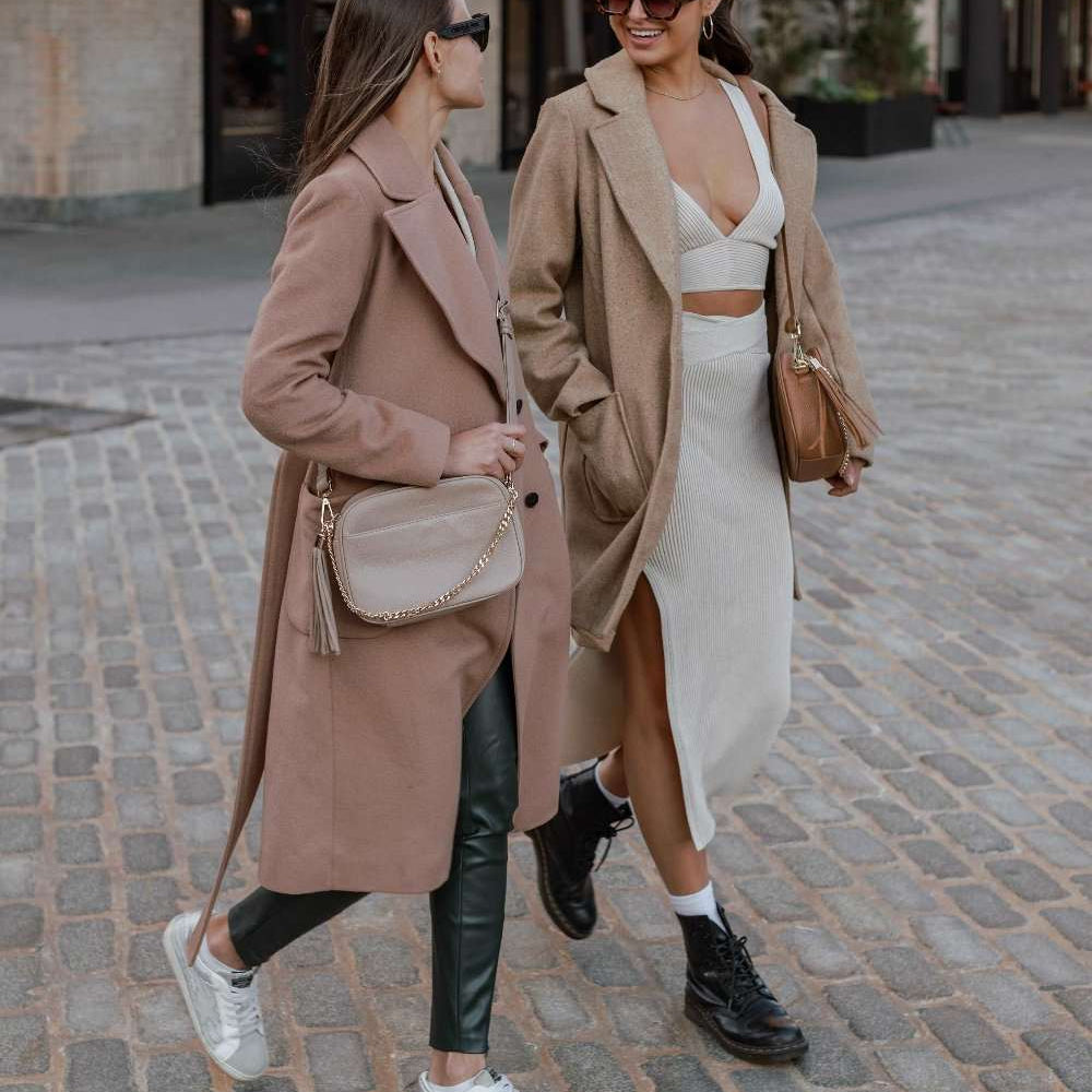 Two women walking down the street, each carrying a Bestie Crossbody Bag from Tottie—one in stone color and the other in tan