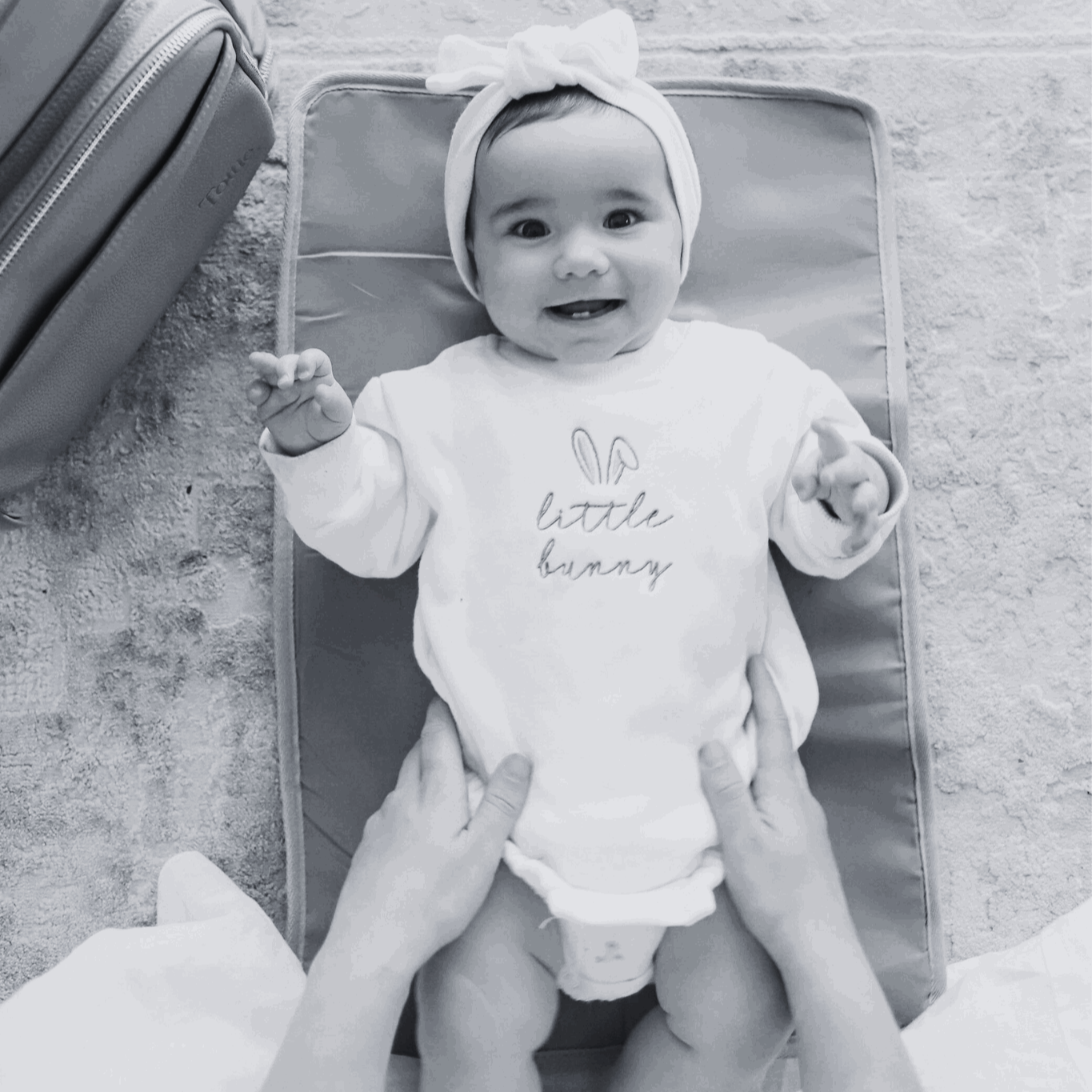 Black and white image of a baby on a Tottie's nappy change mat
