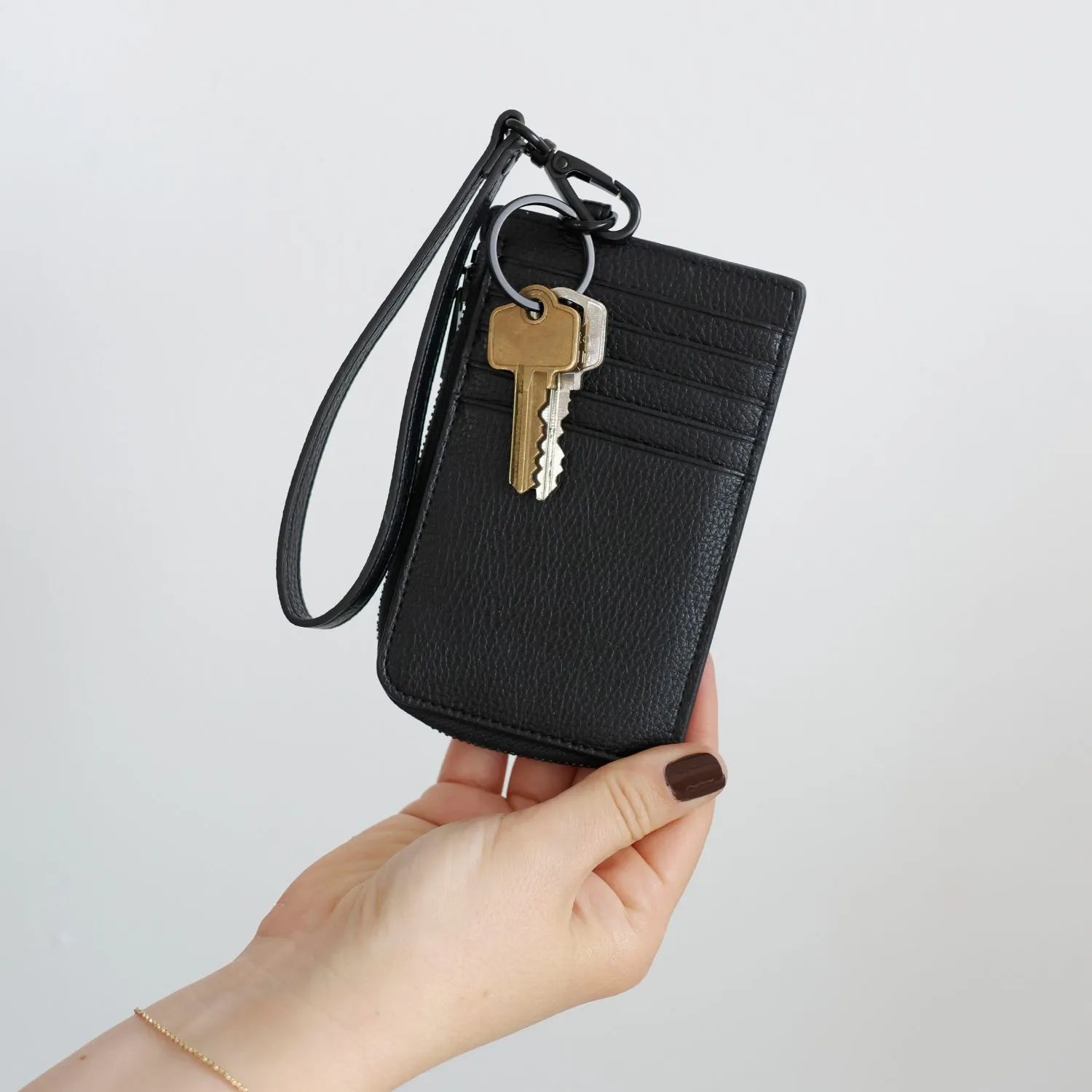 Hand holding a black card holder wristlet wallet