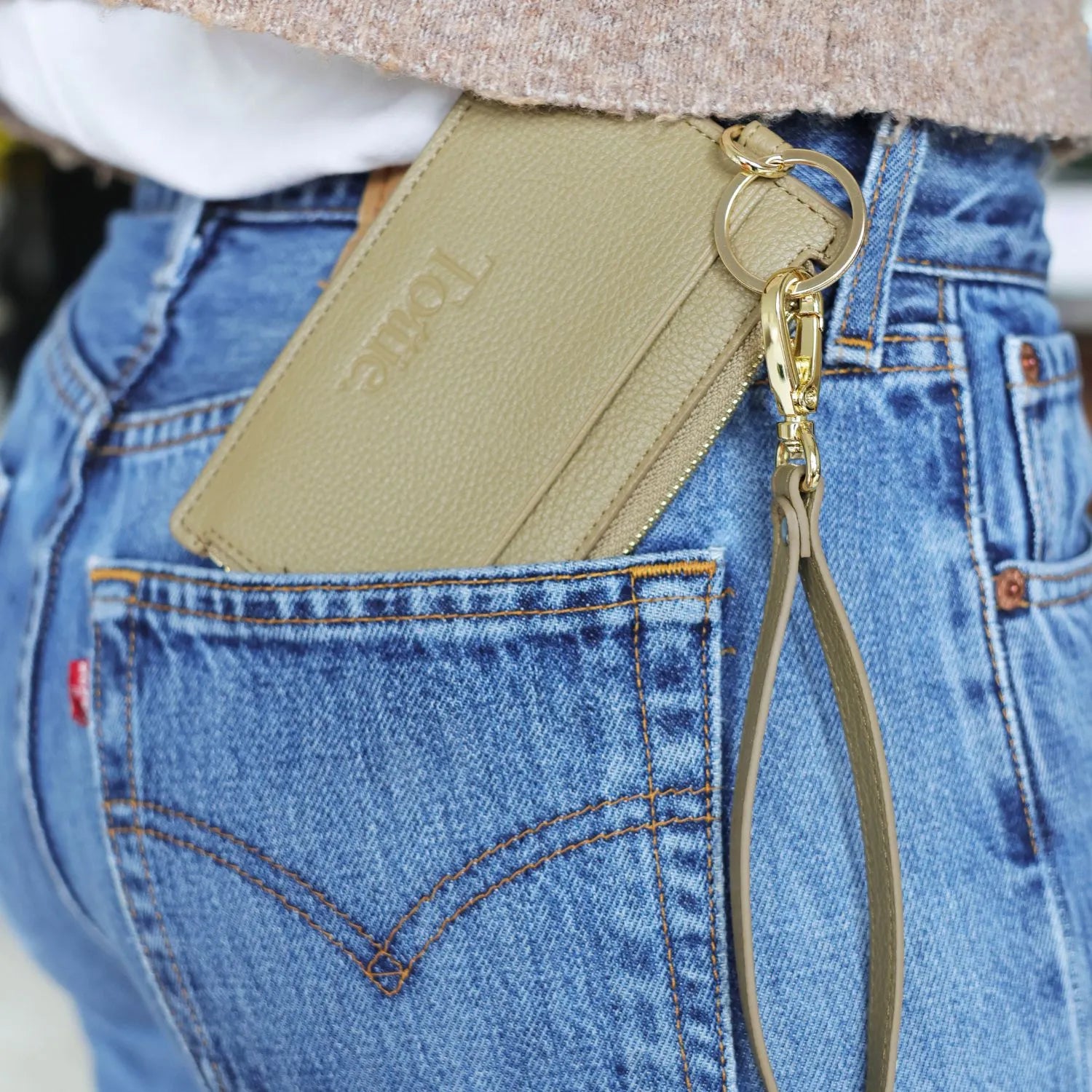 Card holder wallet in khaki colour placed in the back pocket of jeans.