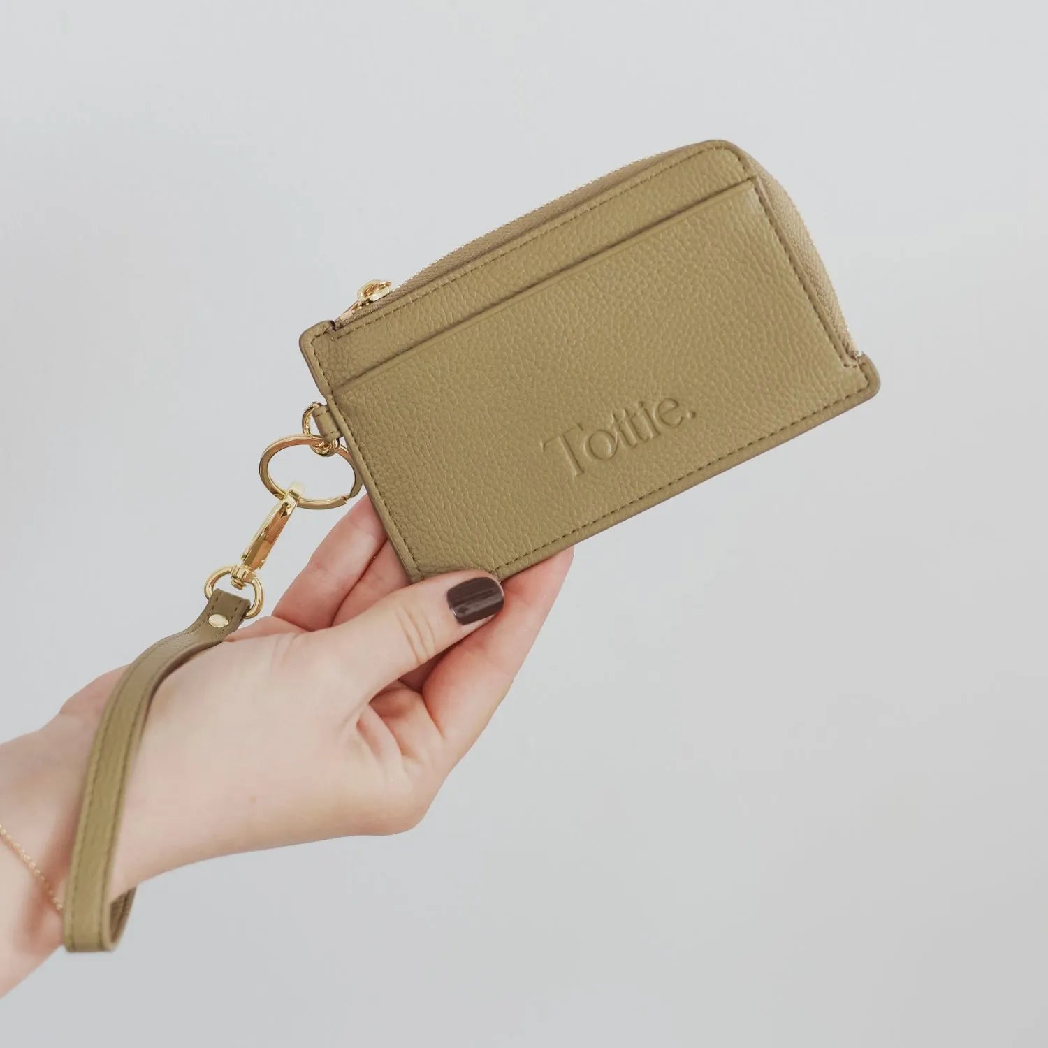 Stylish khaki card holder wallet wristlet in hand.