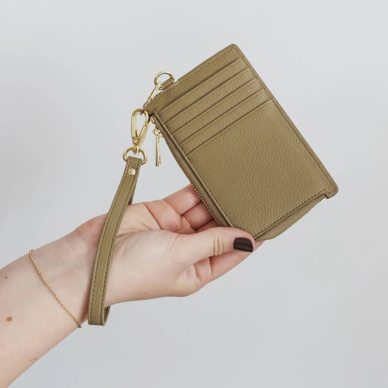 Hand holding a khaki card holder wallet wristlet
