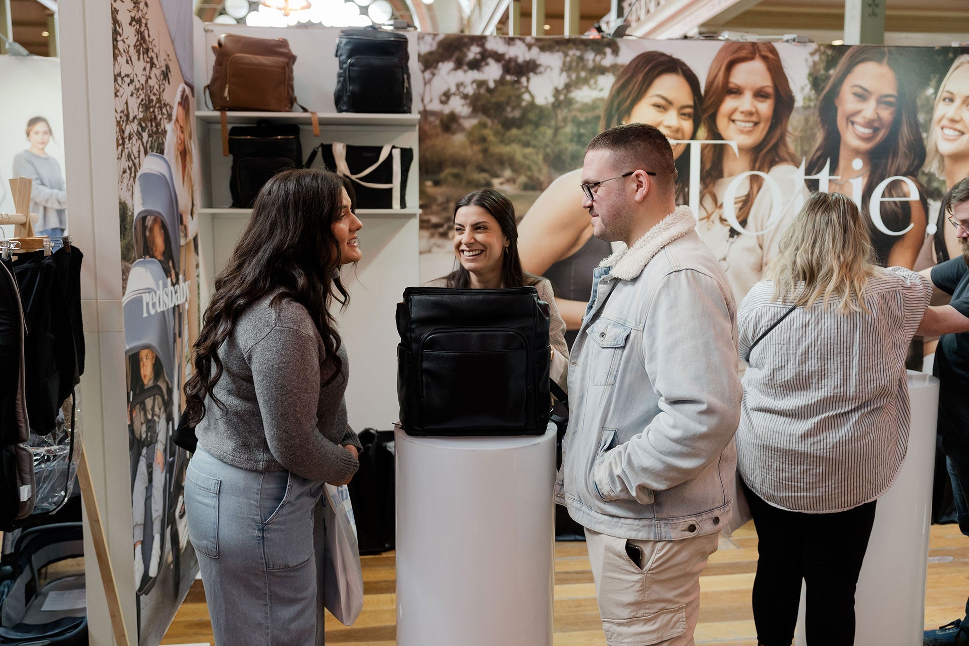 Black Friday Australia shopping scene featuring Tottie bags, new mum and dad, and sales staff at the booth.