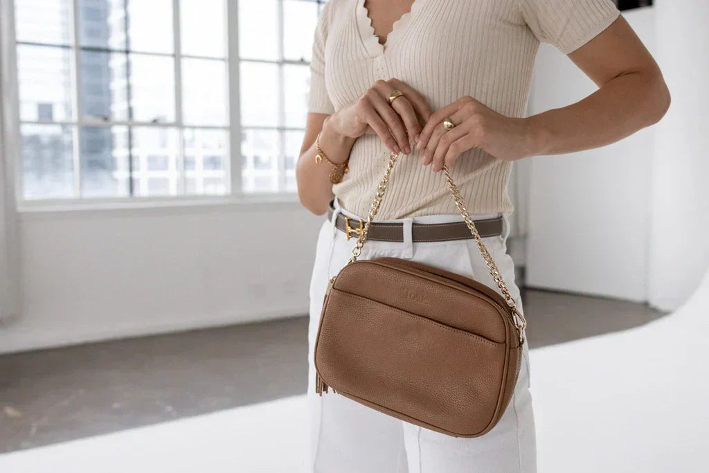 Woman in smart casual at an office holding a brown crossbody bag for work and weekends