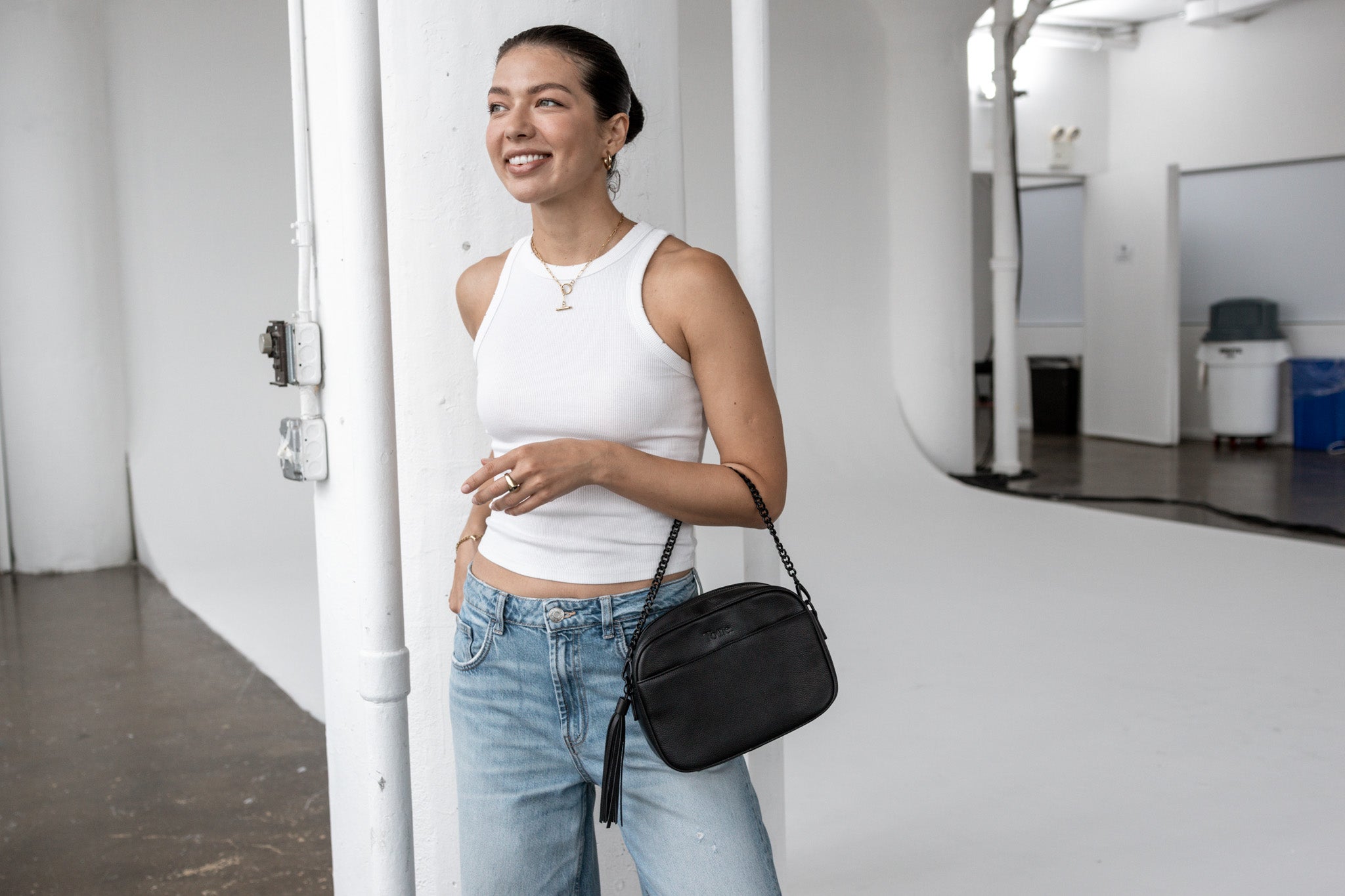 Fashionable black crossbody bag on a woman wearing a white sleeveless top – versatile for day-to-day wear.