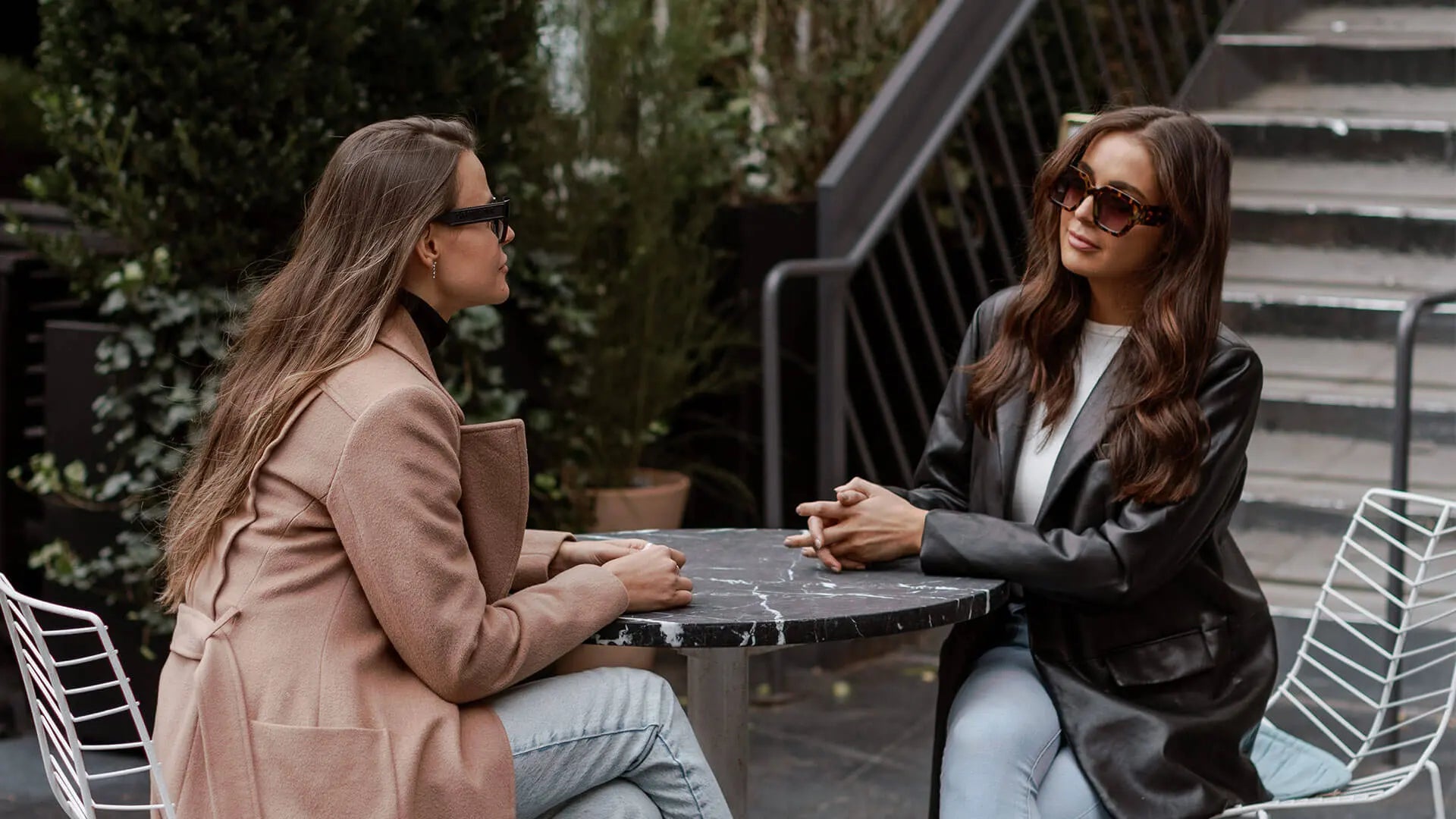 two mothers at an al fresco coffee shop sharing advice for new parents