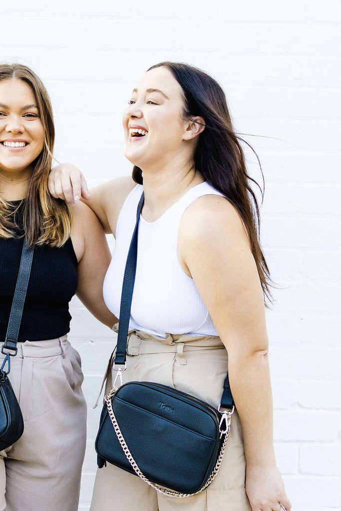 two women carrying a black leather crossbody bag 