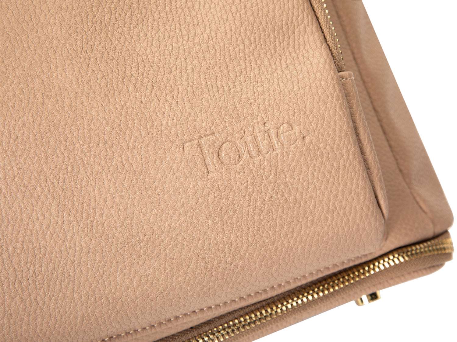 Close-up view of the Tottie logo on a stone leather nappy backpack with a gold zipper from Tottie