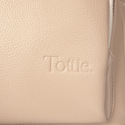 Beige leather travel backpack with 'Tottie' branding on a beige background