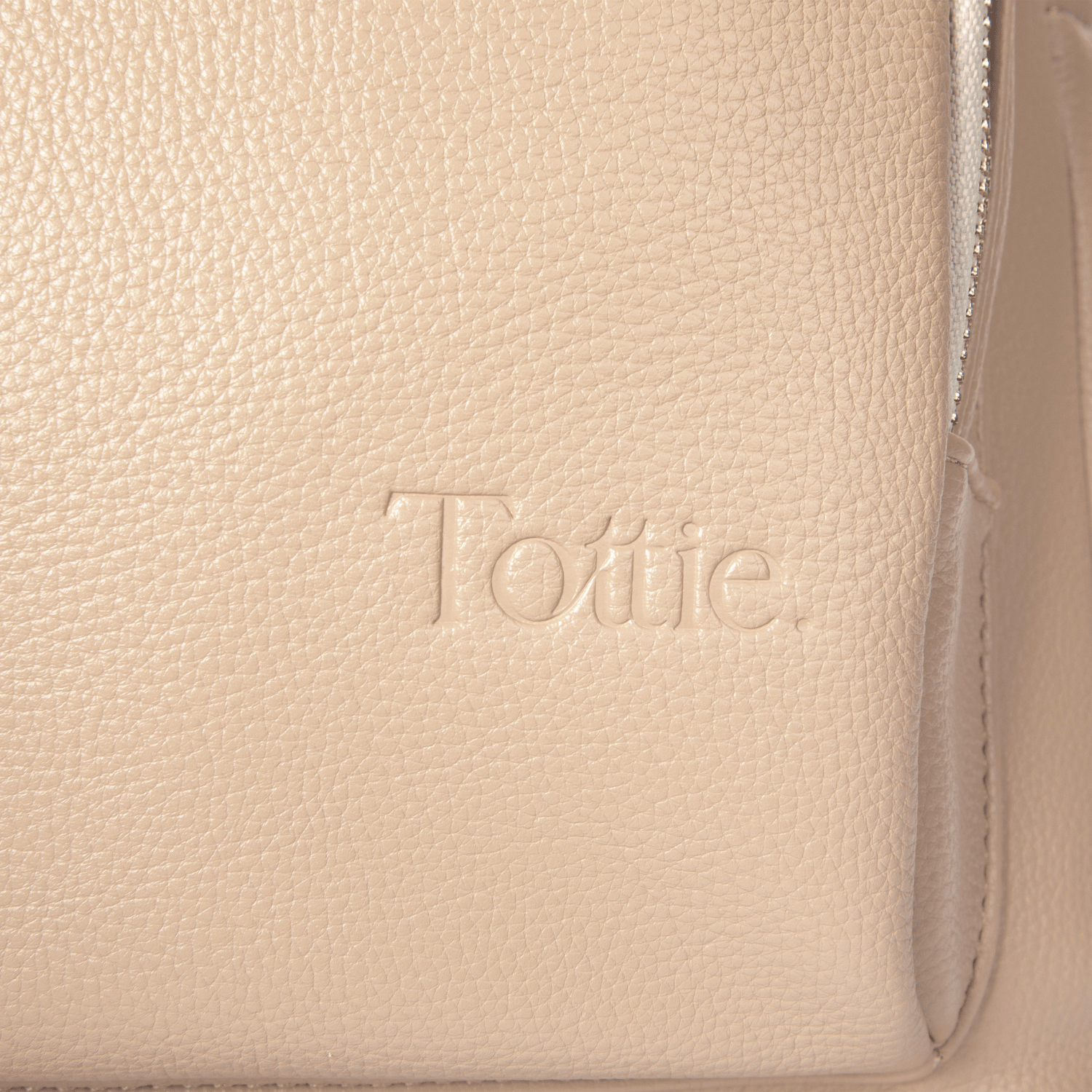 Beige leather travel backpack with 'Tottie' branding on a beige background