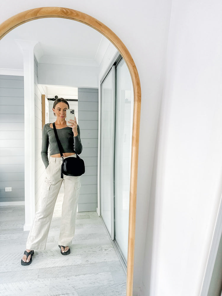 woman taking selfie in front of a mirror with her black leather crossbody bag