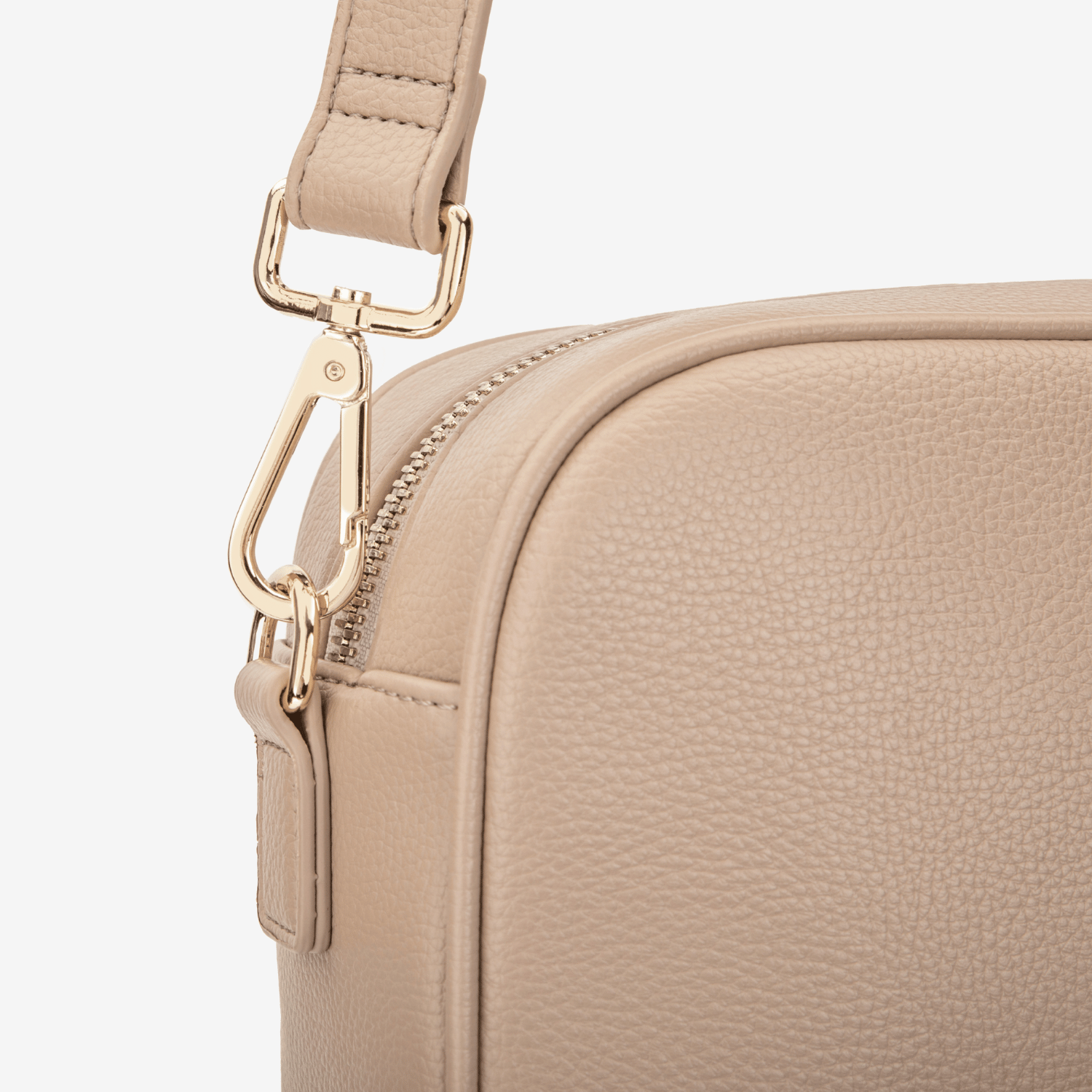 Beige crossbody bag with gold zipper and strap on a white background