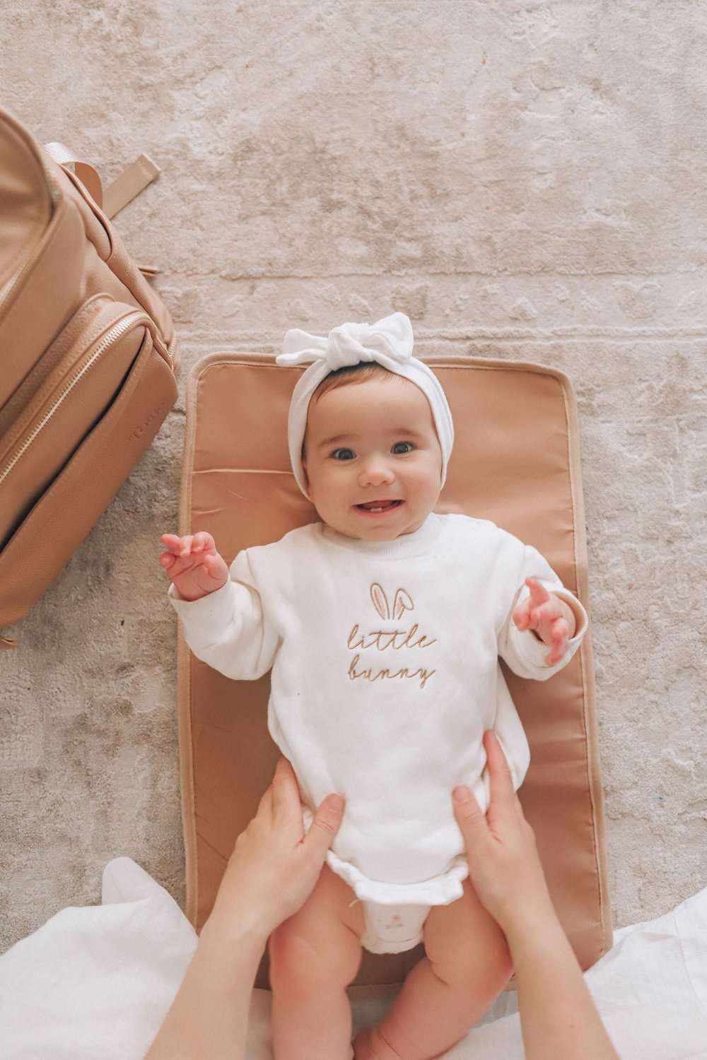 A baby sits on a soft tan colour change mat