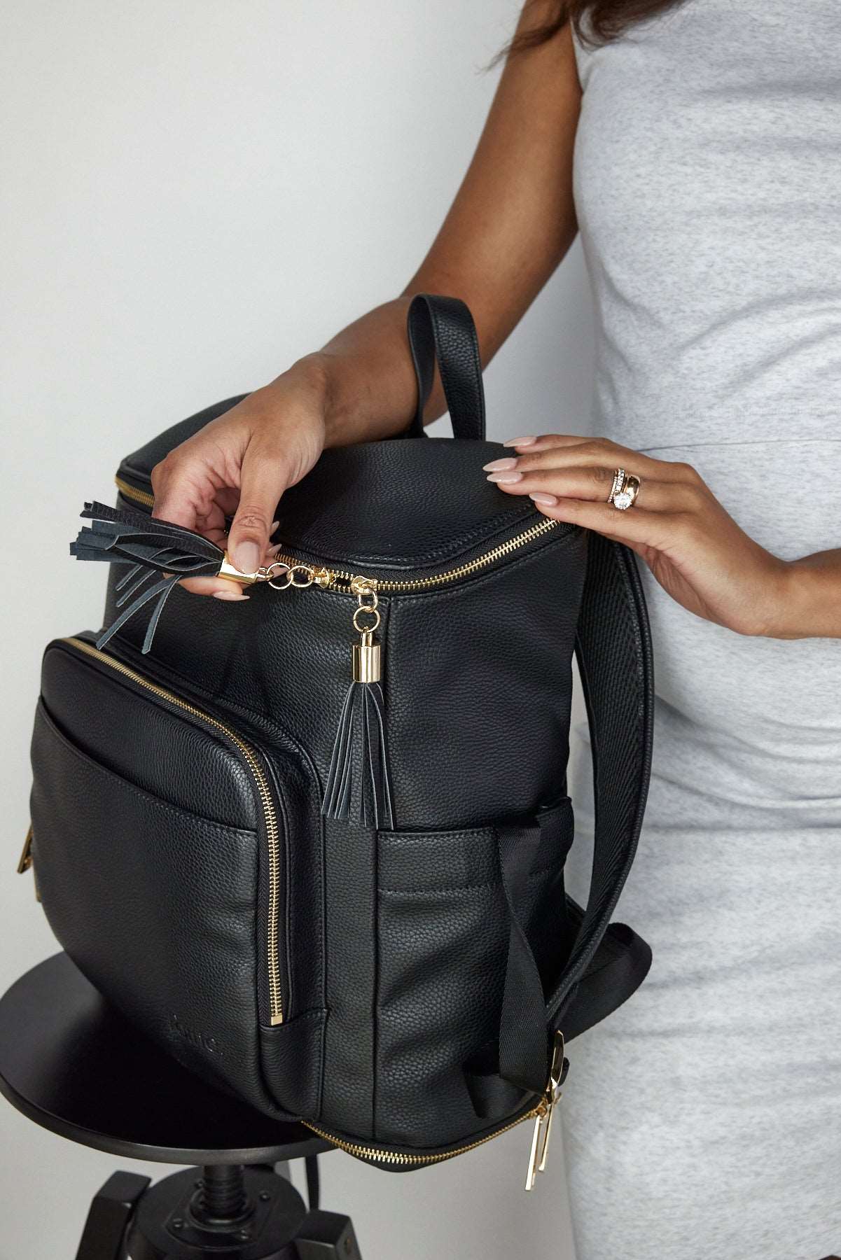 A woman unzipping a black Travel Backpack