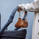 Black stroller with Tottie's pram clips  in tan attached to a tan bum bag from Tottie