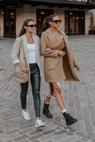 Two women stroll down a brick street with a bum bag slung over each