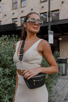 a woman carrying and posing a black bum bag