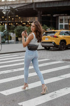 A woman crosses the street carrying a bum bag